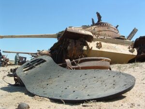 Sole of shoe in forefront with a tank in desert in background