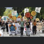 young people marching with signs, banners and smiles