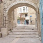 a stone arch over a paved lane in Beit Sahour, with a stone building in the background