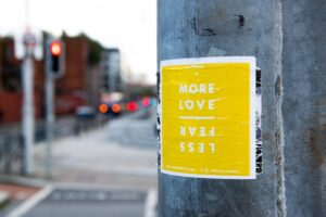 yellow flyer posted on post with words love more fear less 