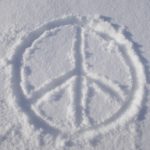 Image of a peace sign drawn in white sand