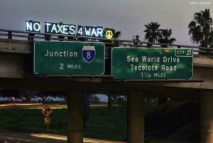 the "no taxes 4 war" illuminated letters visible on an interstate five highway overpass