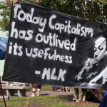 black banner held outside that reads 'Today capitalism has outlived its usefulness'
