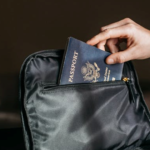 a hand sliding a US passport into a pocket of a black bag